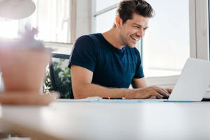a man smiling and looking at a laptop 