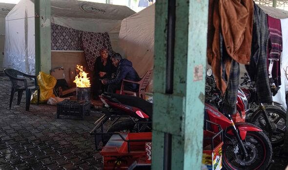 Syrian refugees warm themselves with fire in front of tents in southern Turkey