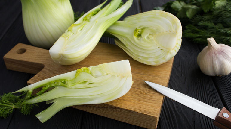 fennel sliced with knife on cutting board