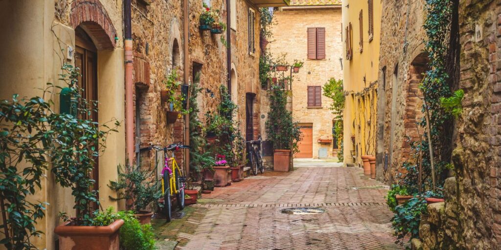 <p><em>Recommended by Sam of <a href="https://www.newenglandwanderlust.com/" rel="noreferrer noopener">New England Wanderlust</a></em></p> <p>If you’re planning to tour the Tuscan countryside, be sure not to miss the small, charming town of Pienza in Central Italy. Located in the province of Siena, this little town underwent a transformation in the mid-1400s when Pope Pius II decided he wanted his hometown to become the “ideal village” and began construction of several buildings to turn Pienza into what it is today. </p> <p>Now, Pienza truly is an ideal Tuscan town that provides the most amazing views of the Val d’Orcia, is home to some incredible Renaissance architecture, and is also the birthplace of Pecorino di Pienza cheese. </p> <p><strong>Main Piazza</strong></p> <p>Be sure not to miss Pienza’s main piazza to witness the beautiful buildings erected during the town’s transformation. Some of the ones to look for are the Duomo, Palazzo Piccolomini, and the beautiful stone well, Pienza Pozzo dei Cani. And as you walk around, the smell of the cheese shops will entice you inside, so be sure to pop into one of the many shops for a Pecorino di Pienza tasting and take some home with you.</p> <p><strong>Wander the Town</strong></p> <p>The best thing to do in Pienza is to wander the town’s idyllic side streets and walk along the bastions to enjoy the views of the rolling hills and Tuscan countryside. From a distance along the bastions, you’ll even be able to see Agriturismo Terrapille, which was featured at the end of the movie Gladiator. </p> <p>Try to time the sunset with aperitivo at Idyllium, a wonderful cocktail bar with outdoor tables that have a perfect view of the sunset. It’ll be a magical experience and the best way to end your day in Pienza.</p>