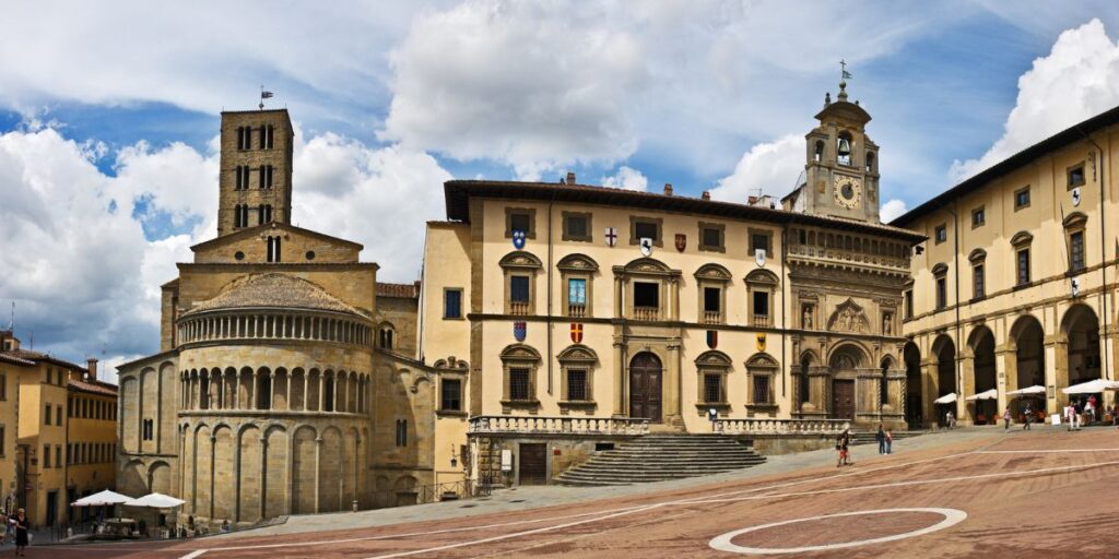 <p><em>Recommended by Martina of PlacesOfJuma.com</em></p> <p>The city of <a href="https://www.placesofjuma.com/arezzo-italy/" rel="noreferrer noopener">Arezzo</a> is undoubtedly one of the most beautiful places in central Italy, and on top of that, an insider tip for sightseeing in Tuscany. Especially the medieval old town is a real jewel, which should not be missed during any perfect trip. Arezzo is located just 1 hour’s drive southeast of Florence and is therefore easy and quick to reach by car, but also by public bus.</p> <p><strong>Ceramics and Jewelry</strong></p> <p>World famous is the noble ceramics but also the fine metalworking of Arezzo. Since time immemorial, handicrafts and jewelry have been produced here, which has helped the city to great prosperity and wealth.</p> <p>Even today, more than ten tons of gold are processed per month. On a stroll through the city center, you will find countless stores selling the finest jewelry and beautiful ceramics, such as the world-famous Aretin vases.</p> <p>In addition, one also discovers numerous stores with antiques, in which there are also one or other treasures to be found.</p> <p><strong>Old Town Arezzo</strong></p> <p>The absolute highlight, however, is the beautiful old town of Arezzo. There, the most important attraction is the Piazza Grande, a breathtakingly beautiful main square and a genuinely unique popular photo motif.</p> <p>The unique feature: it slopes downwards at an angle, creating an almost surreal backdrop. An accurate insider tip is the sizeable antique market that takes place there once a month. </p> <p>Also worth seeing are the many exciting museums, excavation sites, and beautiful churches, where art treasures and masterpieces by famous artists such as Piero della Francesca or Giorgio Vasari can be admired.</p>