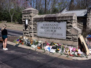 A woman pauses as she visits a memorial at the entrance to The Covenant School, March 29, 2023, in Nashville, Tenn.