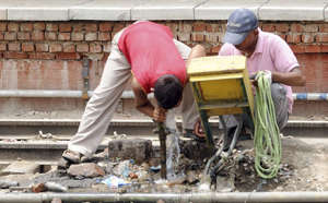 Indian workers drink water from a leaking pipe near the railway track in New Delhi, May 2010, as temperatures in the capital soared above 45 degree Celsius. RAVEENDRAN/AFP
