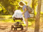 Mother cover her little baby in a stroller with a blanket while out for a walking on a sunny summer afternoon