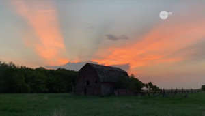 Brilliant rays of the setting sun illuminate the sky and the farms of Manitoba