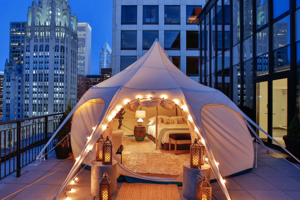 <p>Need to go off-grid in baby steps? Urban glamping is the answer. <a href="https://www.thegwenchicago.com/accommodations/glamping/" rel="noopener noreferrer">The Gwen</a>, one of Chicago's historic downtown high-rises and a member of The Luxury Collection of hotels, sets up "camp" on its 16th-floor terrace from May through the end of September. Anxious city folk will be comforted by the sounds of Michigan Avenue and the ability to pop next door to Nordstrom to pick up a spare pair of shorts.</p> <p>The Lotus Belle tent is 16 feet in diameter and filled with boho-design delights like drum-shaped mango wood side tables, hand-knotted macramé cushions, bronze Malta lanterns and a braided jute rug. Their glamping package includes welcome bites and access to a suite that has a wet bar and dining room, round-trip airport transportation and gold-leaf-garnished gourmet s'mores at turndown.</p> <p class="listicle-page__cta-button-shop"><a class="shop-btn" href="https://www.thegwenchicago.com/accommodations/glamping/">Book Now</a></p>