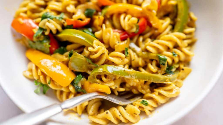 Close shot of a yellow pasta dish in a white ceramic bowl.