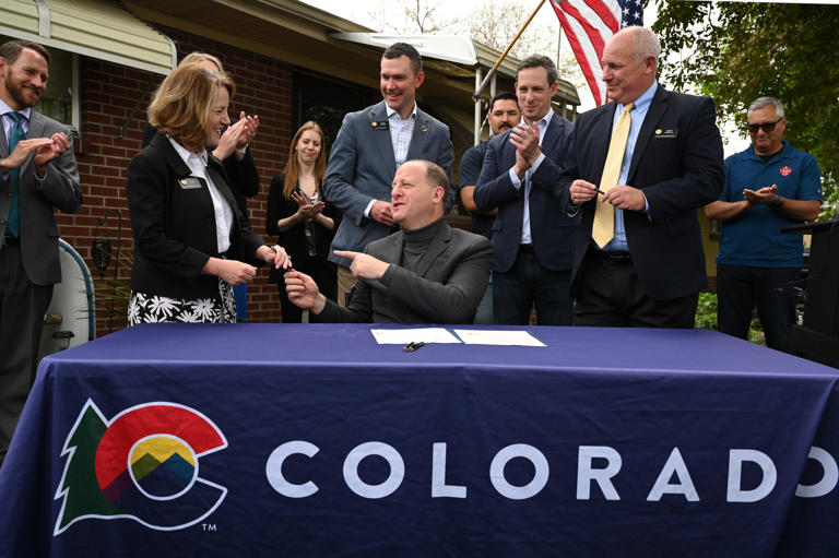 Gov. Jared Polis signed SB23-303, Reduce Property Taxes and Voter-approved Revenue Change and SB23-304, Property Tax Valuation in front of the home of Joe Lloyd Medina, 78, in Commerce City on Wednesday, May 24, 2023.