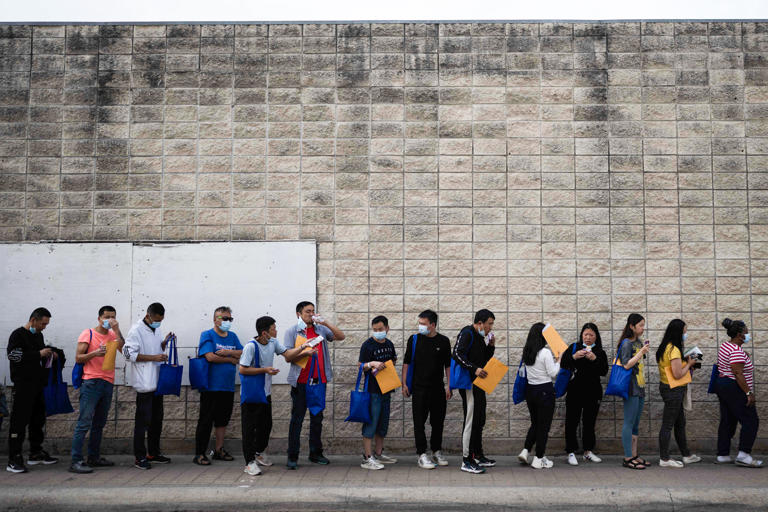 Migrants line up outside a processing center on May 11, 2023 in Brownsville, Texas.