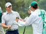 Rory McIlroy trades clubs with his caddie, Harry Diamond, as he walks the first fairway during the second round of the Masters.