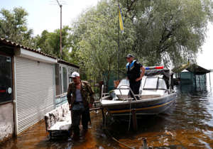 Mykola stands next to a police boat on a flooded island, which locals and officials say is caused by Russia