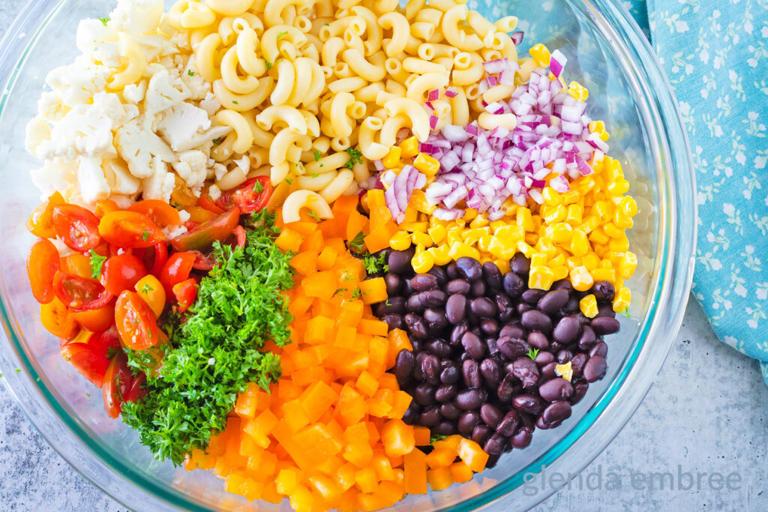 Mexican Macaroni Salad Ingredients in a clear glass mixing bowl.
