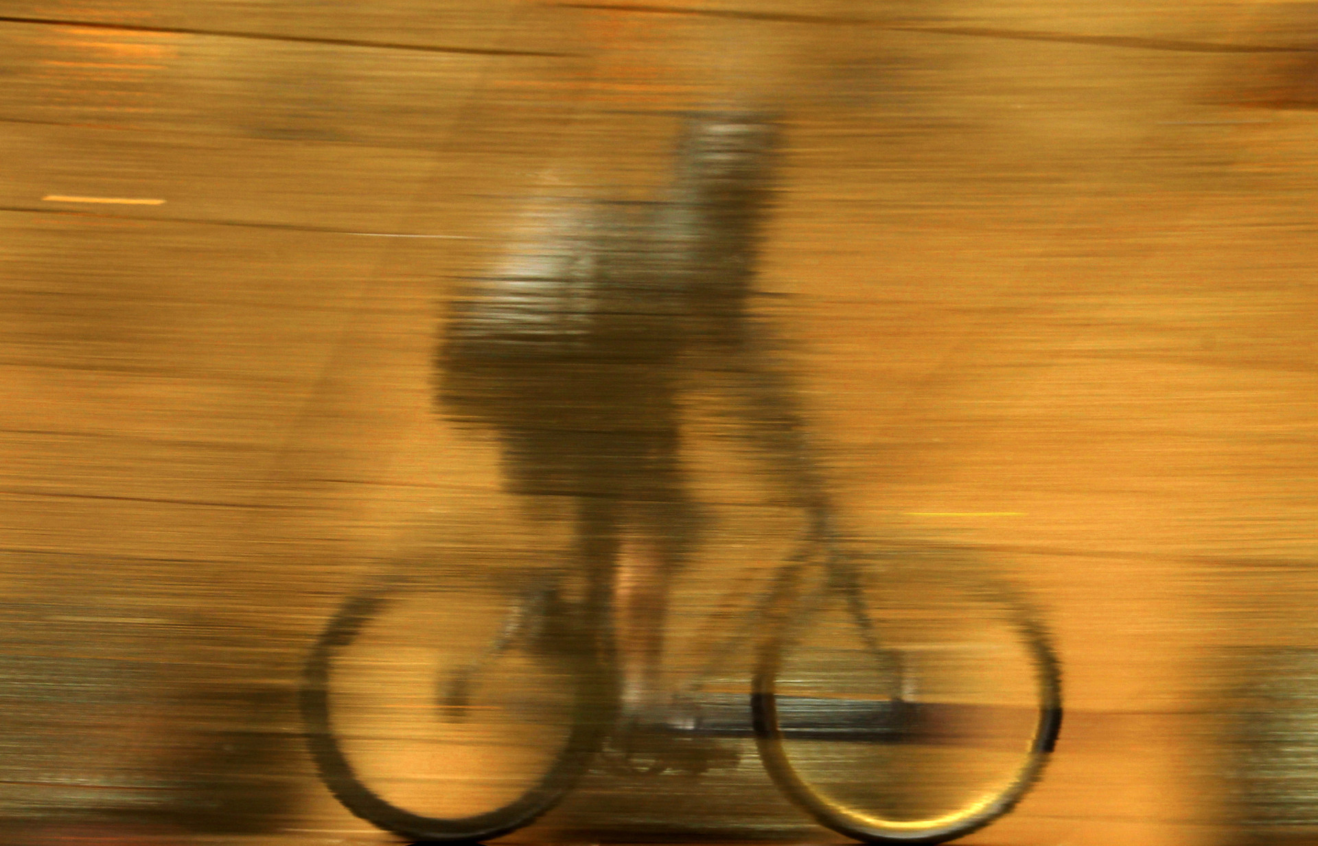 Un trottoir humide dans une rue centrale de Sydney offre le reflet d’un coursier à vélo traversant une averse.