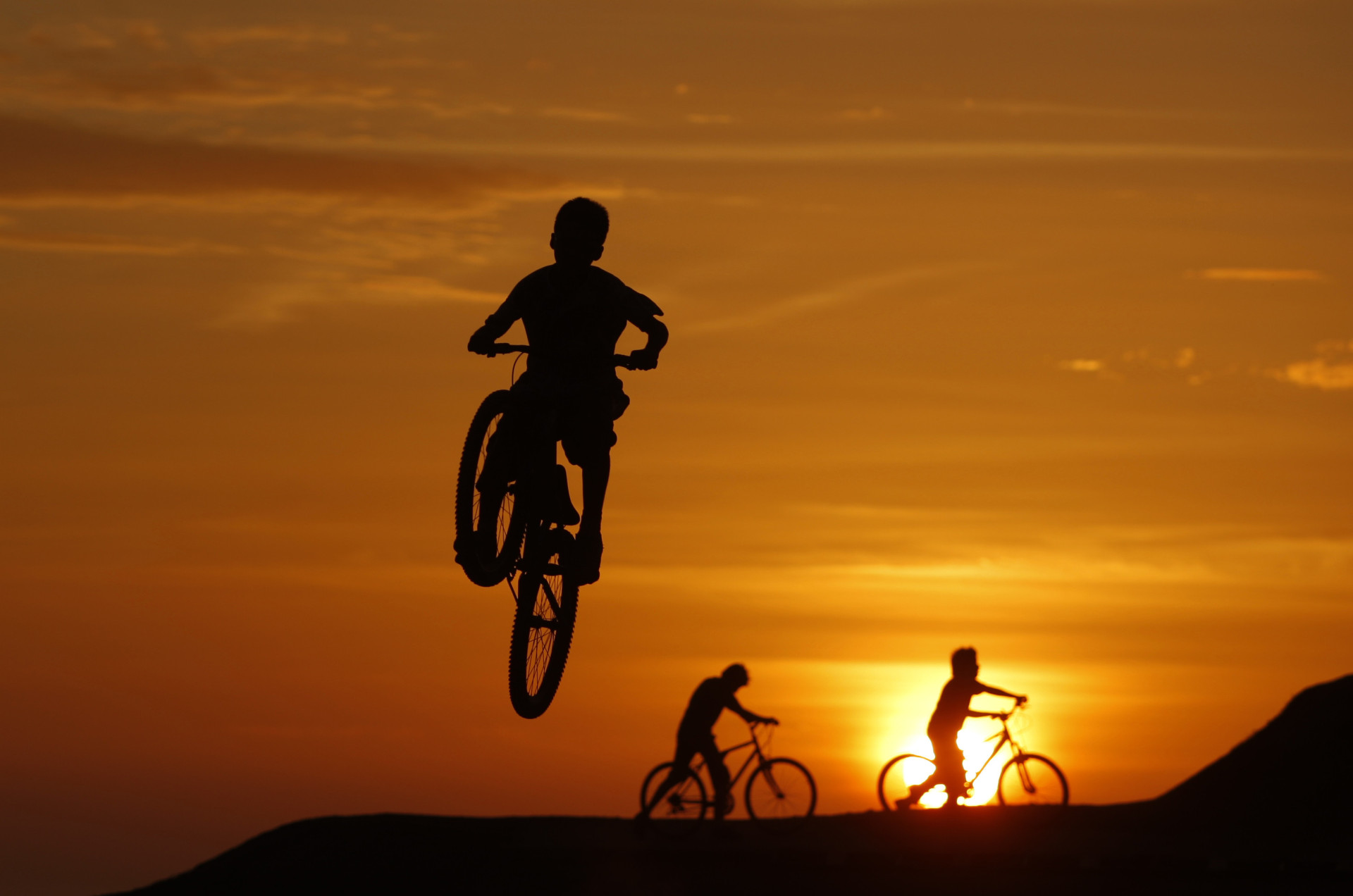 Des jeunes jouent les acrobates à vélo au coucher du soleil, dans un parc de Lima.