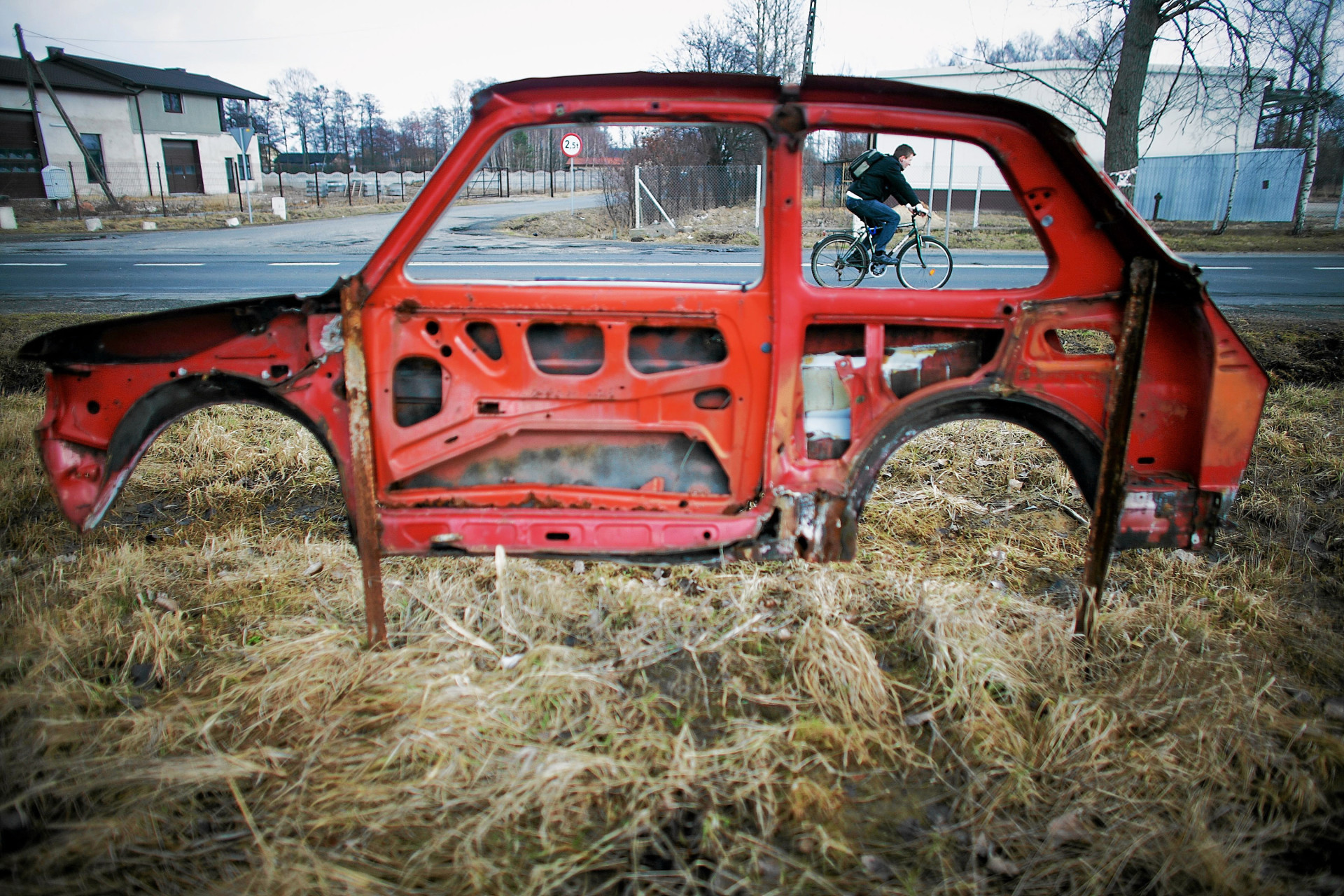 Un cycliste est vu à travers les restes d'une Fiat 126, utilisés pour faire la publicité d'une entreprise de services automobiles, près de Łódź, dans le centre de la Pologne.