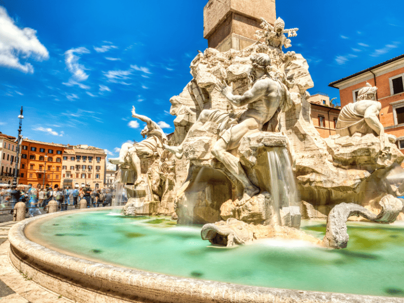 The Fontana dei Quattro Fiumi is a stunningly majestic sight, with its four rivers flowing majestically from the center. And tourists admiring its beauty and grandeur.