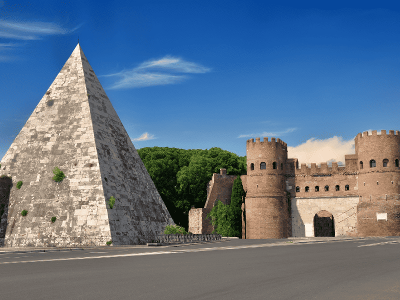A well-preserved, white marble pyramid-shaped structure, the Pyramid of Cestius stands tall near the Porta San Paolo in Rome, Italy.