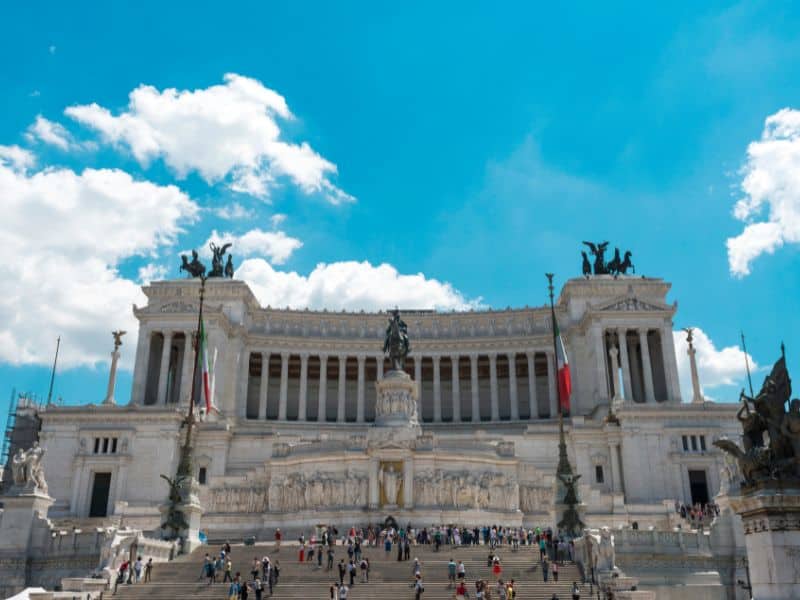 Immerse yourself in the lively energy of Piazza Venezia in Rome, where locals and tourists come together to admire the impressive Vittorio Emanuele Monument up close, snapping photos and marveling at its grandeur while soaking in the vibrant atmosphere of this bustling square.