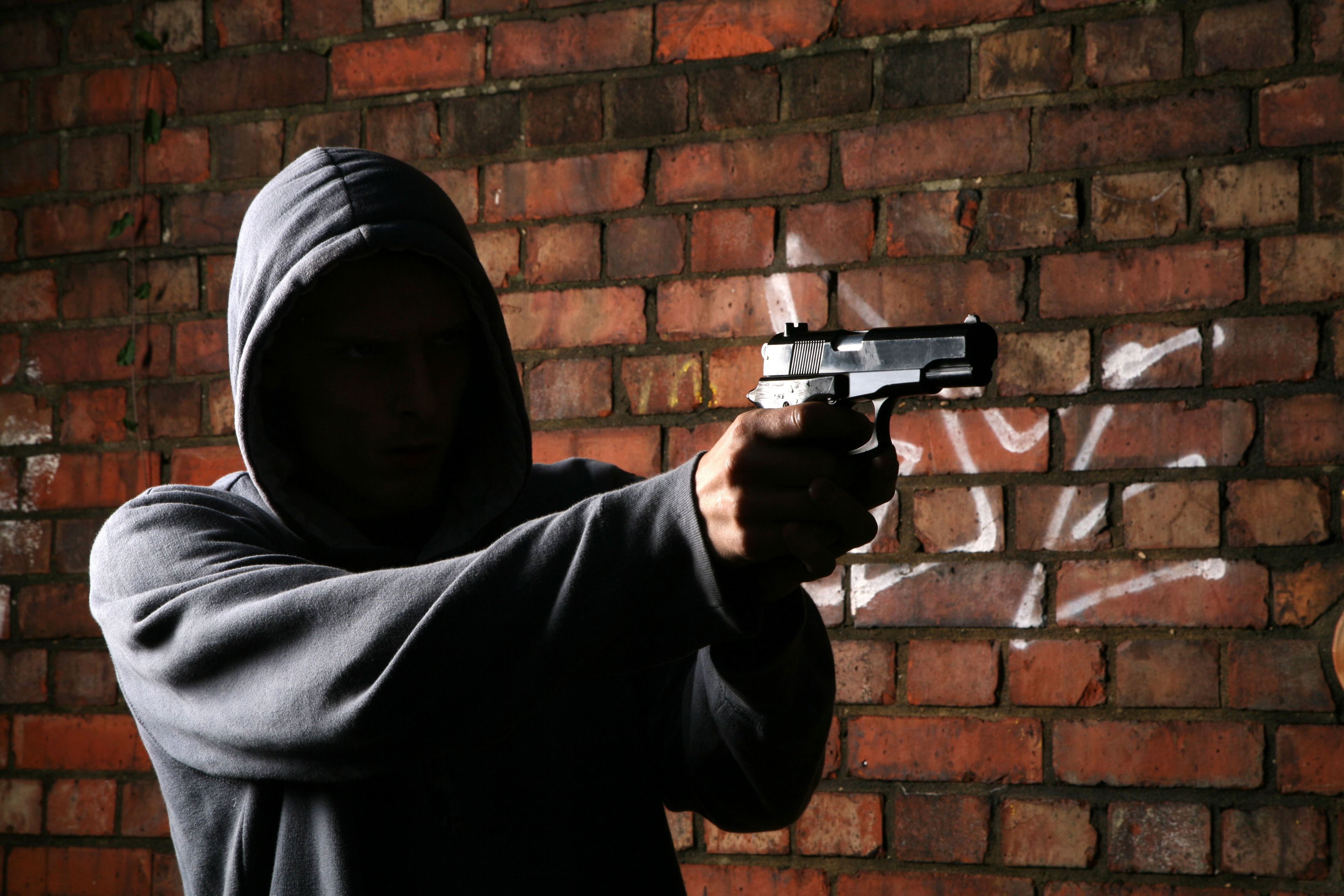 Подросток бандит. Бандит с пистолетом. Мужчина в капюшоне с пистолетом. Бандиты с оружием. Человек в капюшоне с оружием.