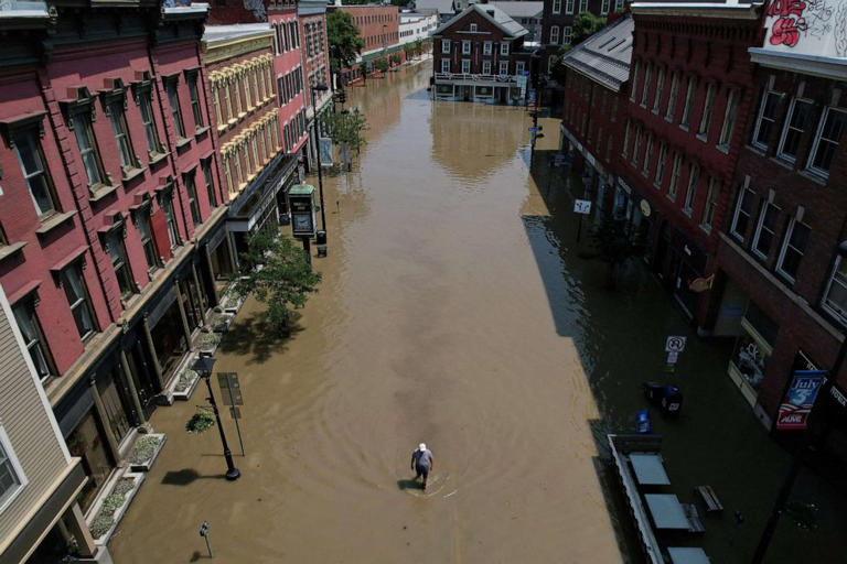 A man walks down a street flooded by recent rainstorms in Montpelier, Vermont, on July 11, 2023.