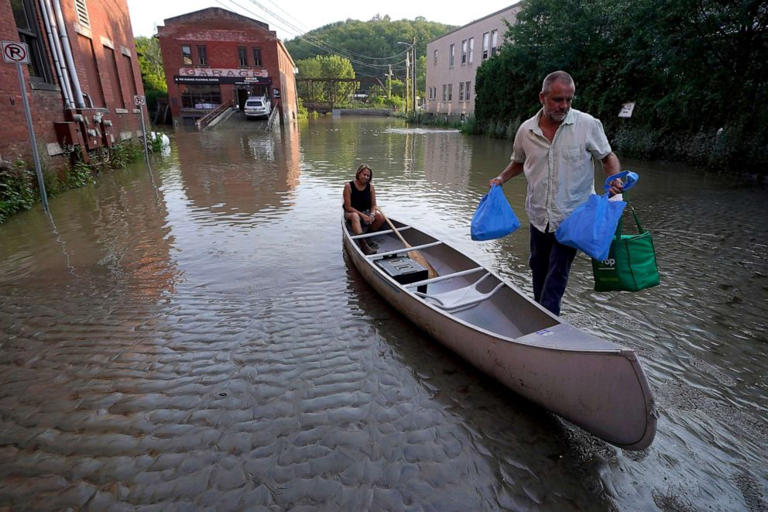 Jodi Kelly, seated center, practice manager at Stonecliff Veterinary Surgical Center, behind, and her husband Veterinarian Dan Kelly, right, use a canoe to remove surgical supplies from the flood damaged center, July 11, 2023, in Montpelier, Vt.