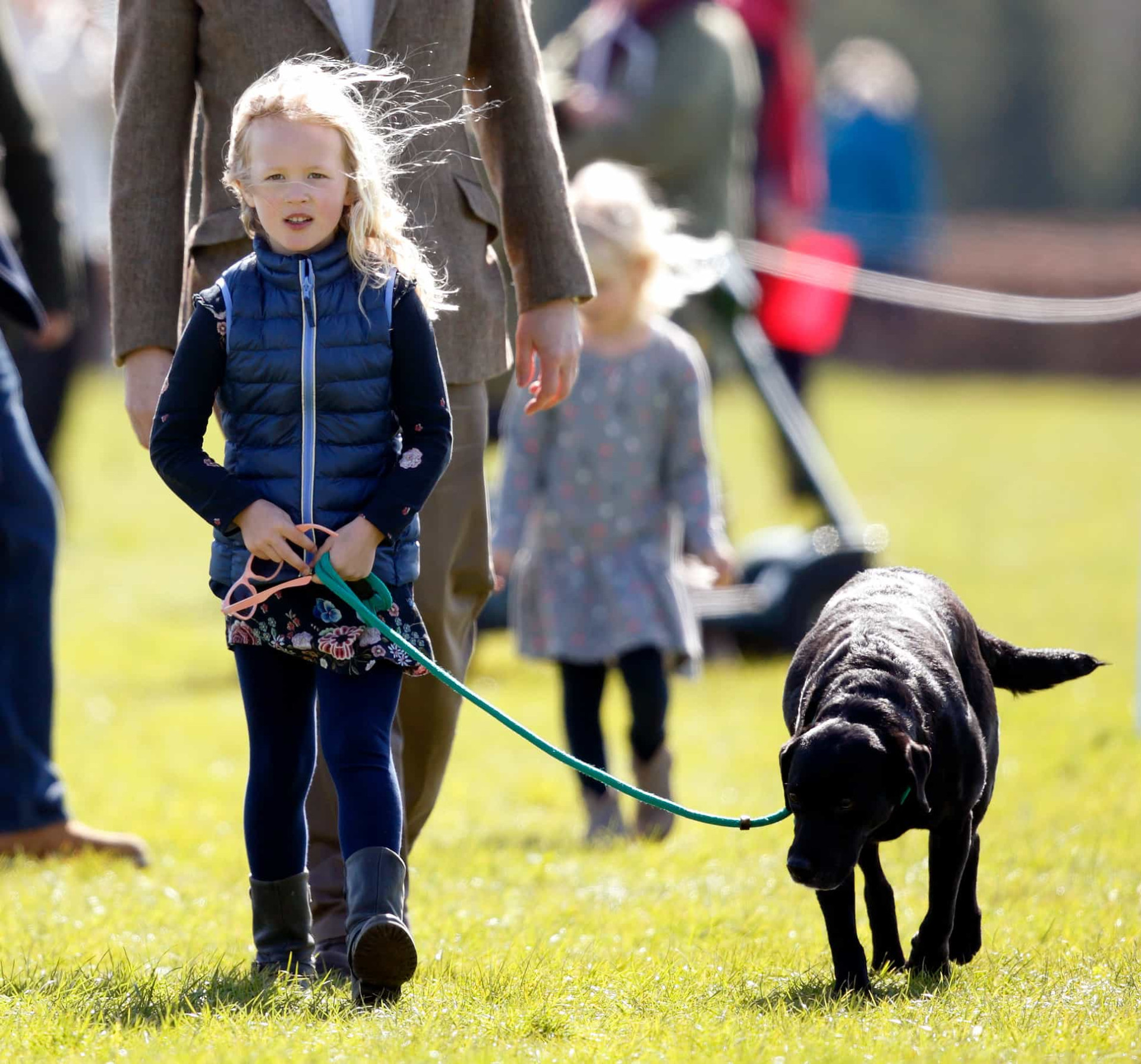 <p>Prinzessin Annes Enkelin, Savannah Phillips, beim Spaziergang mit dem schwarzen Labrador der Familie.</p>