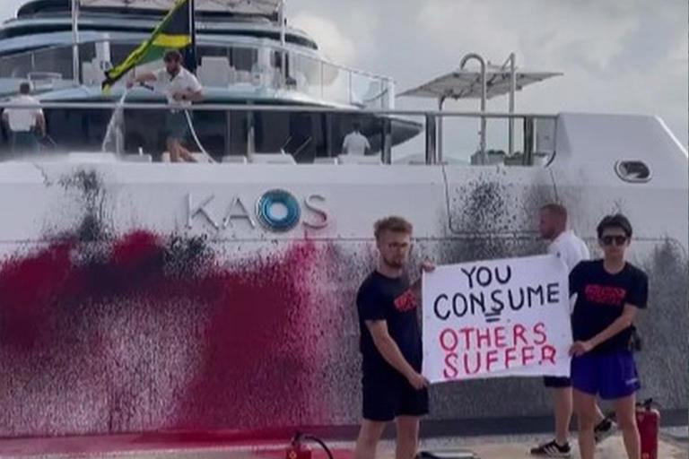 Futuro Vegetal protesters stand in front of Nancy Walton Laurie's superyacht after spray-painting it Sunday.