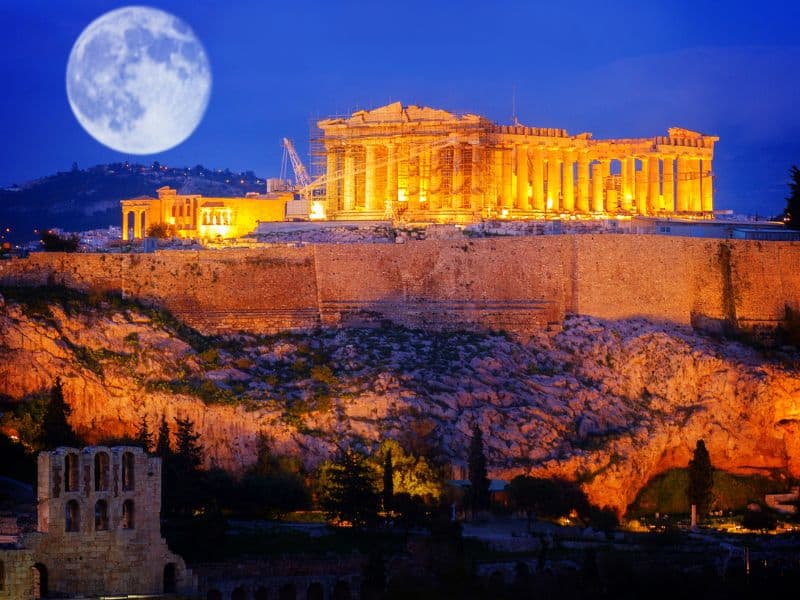 acropolis lit up at night, with a full moon