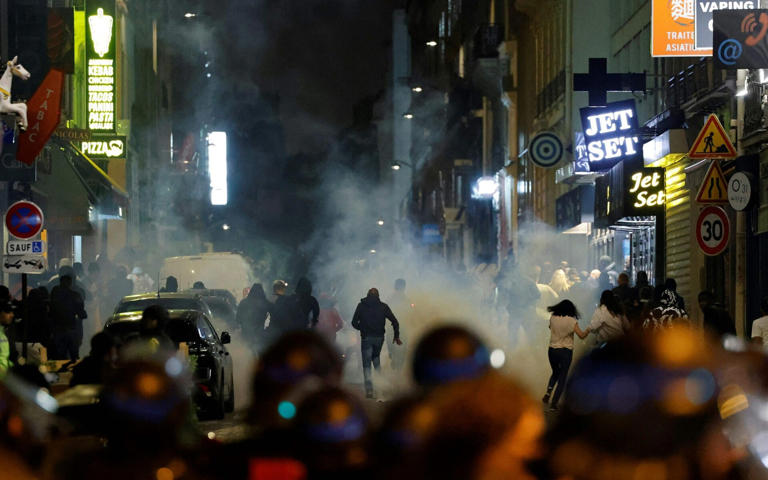 Demonstrators run as French police officers use tear gas in Paris on July 2 - AFP