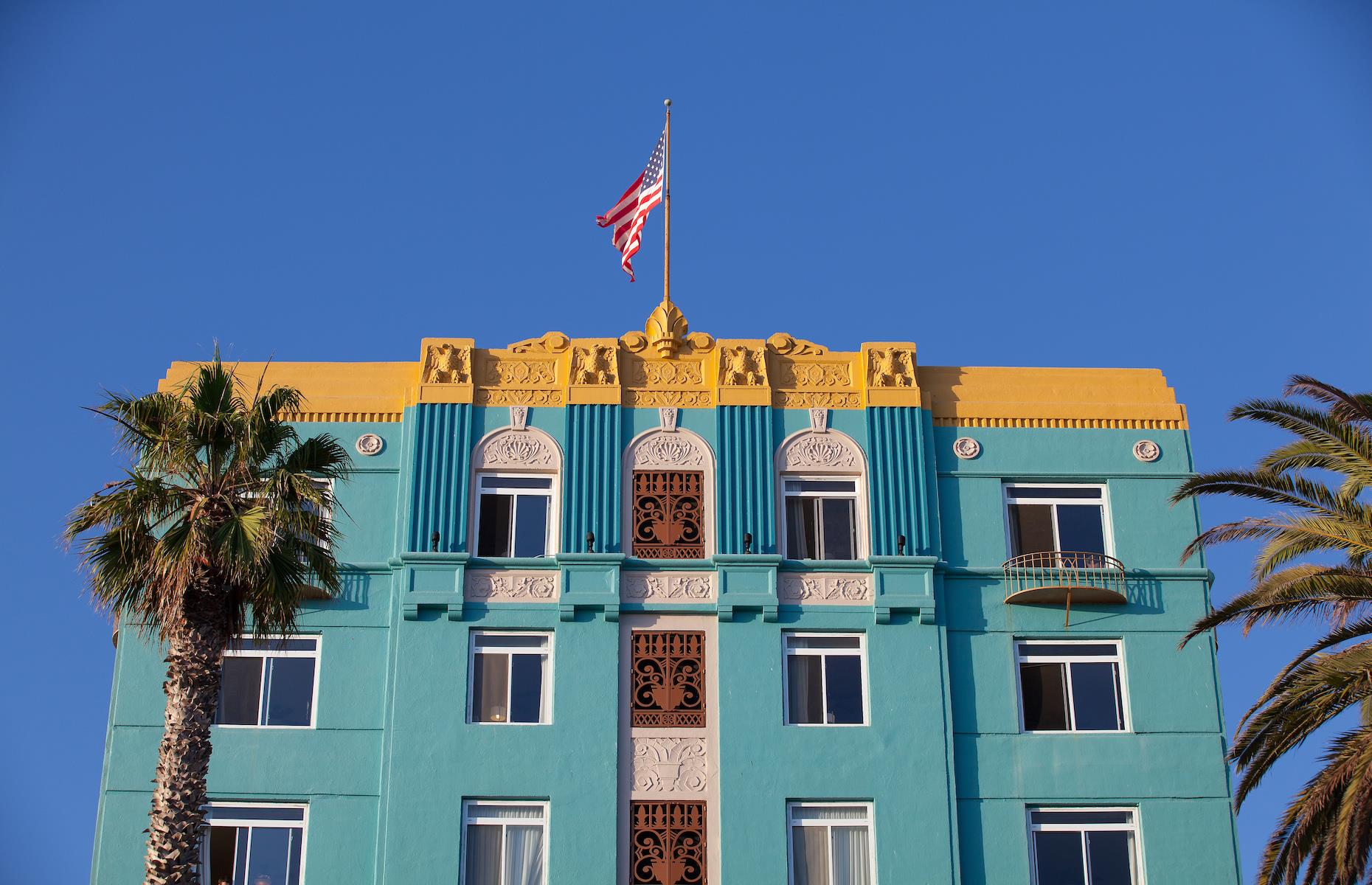 <p><a href="https://www.thegeorgian.com">The Georgian</a> has cut a striking figure on Santa Monica’s oceanside since 1933, when the neighborhood was a sleepy seaside community. Known as Santa Monica’s “First Lady”, the hotel was the vision of Rosamond Borde, a hotelier who commissioned architect M Eugene Durfee to design a grand hotel to attract an affluent crowd. His bold design drew on both the Romanesque Revival and fashionable Art Deco movements. The Georgian was later an exclusive and illicit hangout as one of Los Angeles's first speakeasies. Its star appeal faded in the subsequent decades, but a recent restoration has seen the pastel-hued beauty restored to its former chichi self.</p>