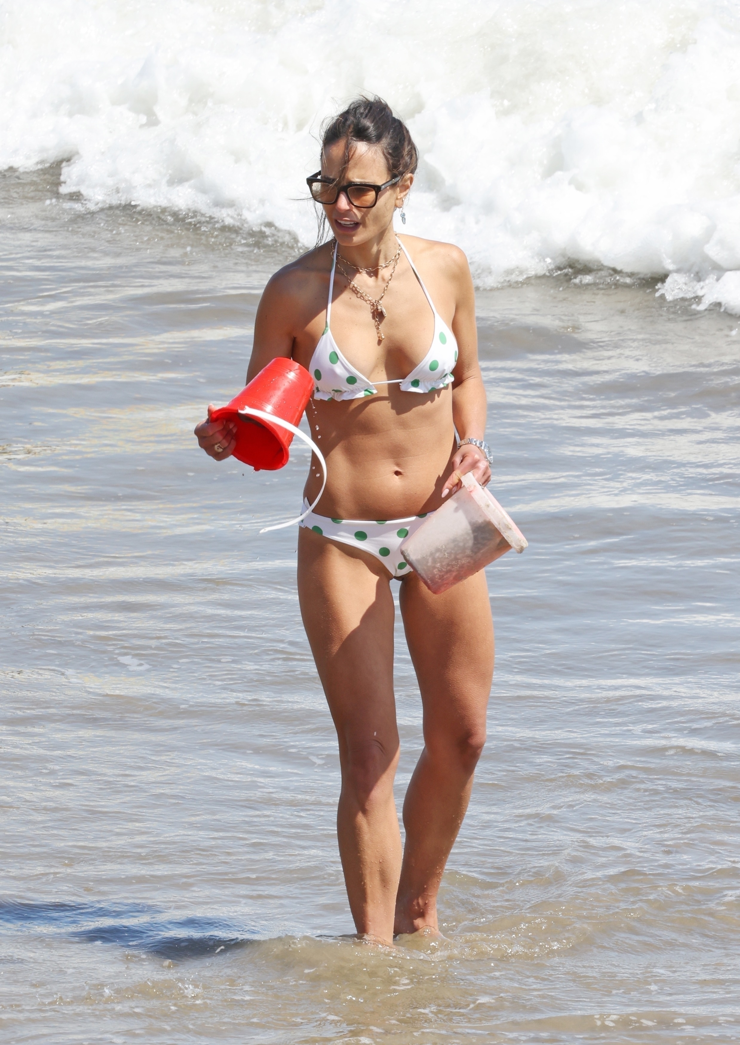 <p>Jordana Brewster waded through the surf with buckets full of sand during a family beach day in Santa Barbara, California, on July 2.</p>