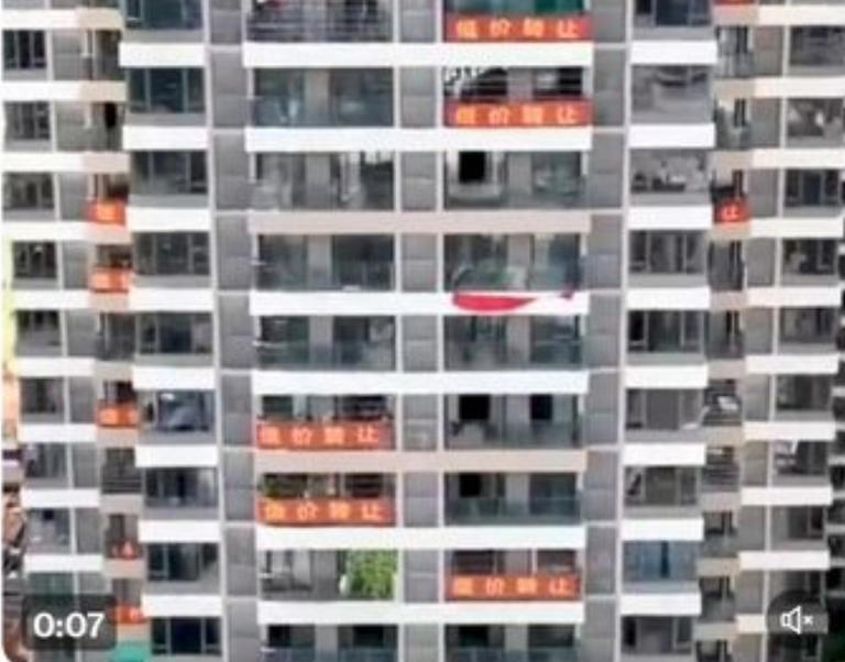中國房市價格崩跌，一棟大樓就有多戶住宅同時掛出銷售布條。   圖 : 翻攝自微博
