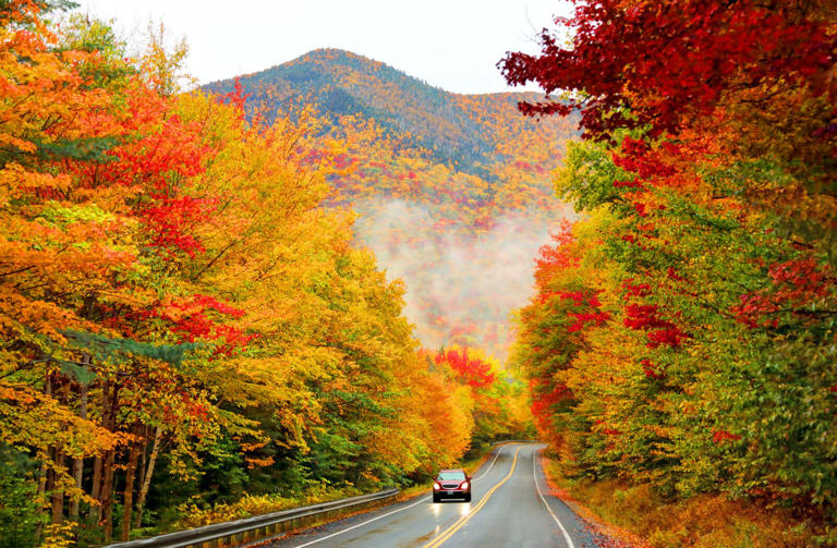 A car drives along Kancamagus Highway in New Hampshire in the fall.