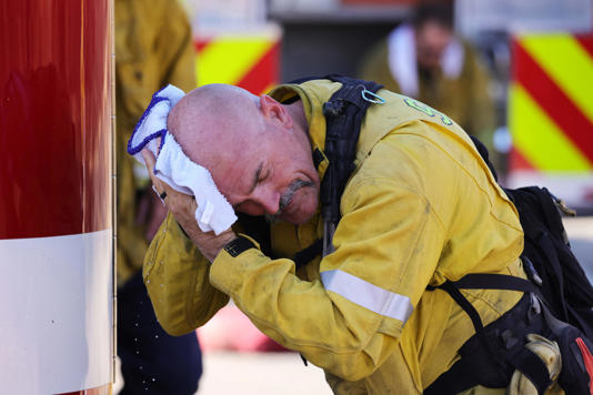 July 19, 2023: A San Bernardino County firefighter wipes his head as the Oak Fire burns near Fontana, California. Millions suffered through intense heat as fires raged, health worries mounted and the world appeared headed for its hottest month of July on record.