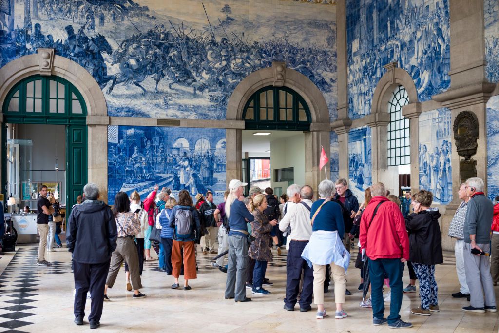 <p>Located in the center of Porto, <a href="https://www.cp.pt/passageiros/pt/consultar-horarios/estacoes/porto-sao-bento">São Bento Station</a> boasts murals constructed from approximately 20,000 azulejo tin-glazed ceramic tiles. The artwork illustrates the story of Portugal’s history, touching on the Battle of Valdevez and the Conquest of Ceuta, as well as other prominent events.</p>