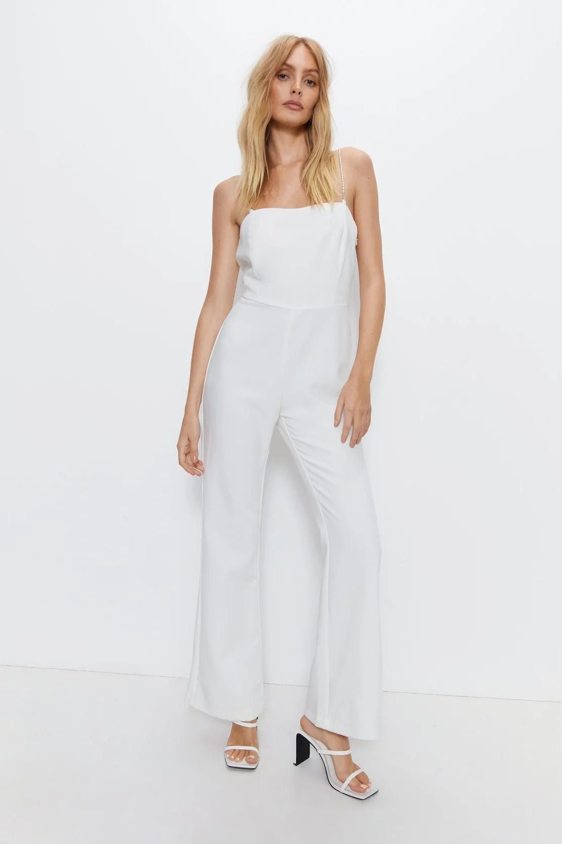 <p><strong>£62.30</strong></p><p><a href="https://www.warehousefashion.com/premium-pearl-strap-jumpsuit/BWW05186.html">Shop Now</a></p><p>Warehouse's bridal jumpsuit features a cool cut-out back design and pretty faux-pearl straps. Wear yours with a matching white blazer for civil ceremonies or jazz it up for Hen do's and engagement parties with platform heels.</p>
