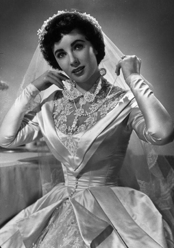 <p>Elizabeth Taylor’s wedding dress did not disappoint in the 1950 movie <em>Father of the Bride</em>. That combo of silk, buttons, collar, and lace is everything you could want in a fictional wedding dress. </p>