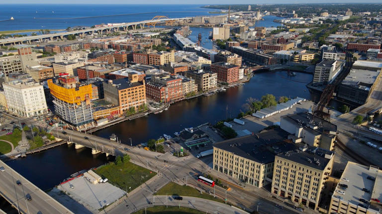 The Milwaukee River runs through the Historic Third Ward, west of the Hoan Bridge, and south of the Milwaukee skyline on Monday, July 10, 2023. Also seen is the in progress 31-story tower (left), known as 333 N. Water, on the Milwaukee River at North Water Street and East St. Paul Avenue.