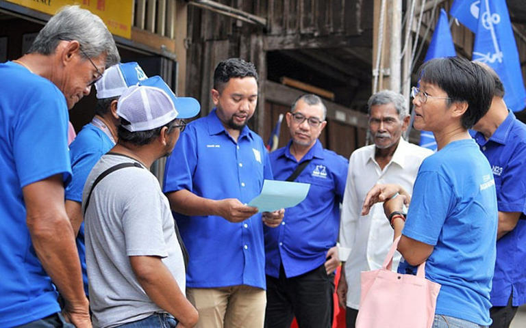 Khairi Afiq Yusof, the BN candidate for Kemasik, Terengganu, reading a list of suggestions presented by members of the Hainanese community in Air Jernih, Kemaman, today. (Utusan Malaysia pic)