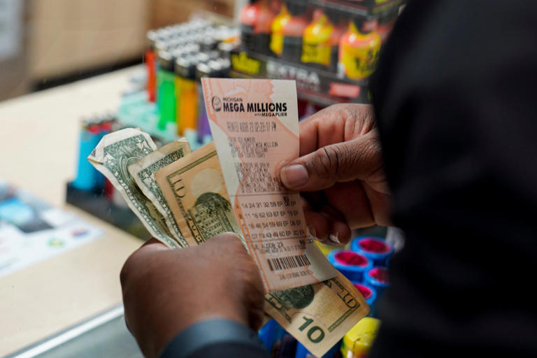 Malik Johnson, 36, of Detroit holds up his purchased Mega Millions lottery ticket on Tuesday, Aug. 8, 2023. The Mega Millions estimated jackpot is up to 1.58 billion dollars and continues to rise as the drawing comes closer. Johnson said he was feeling lucky.