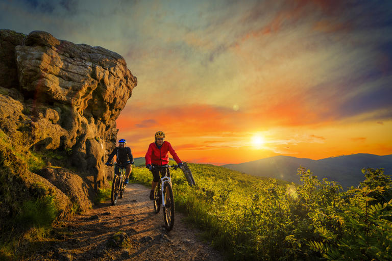 A couple mountain biking at sunset.