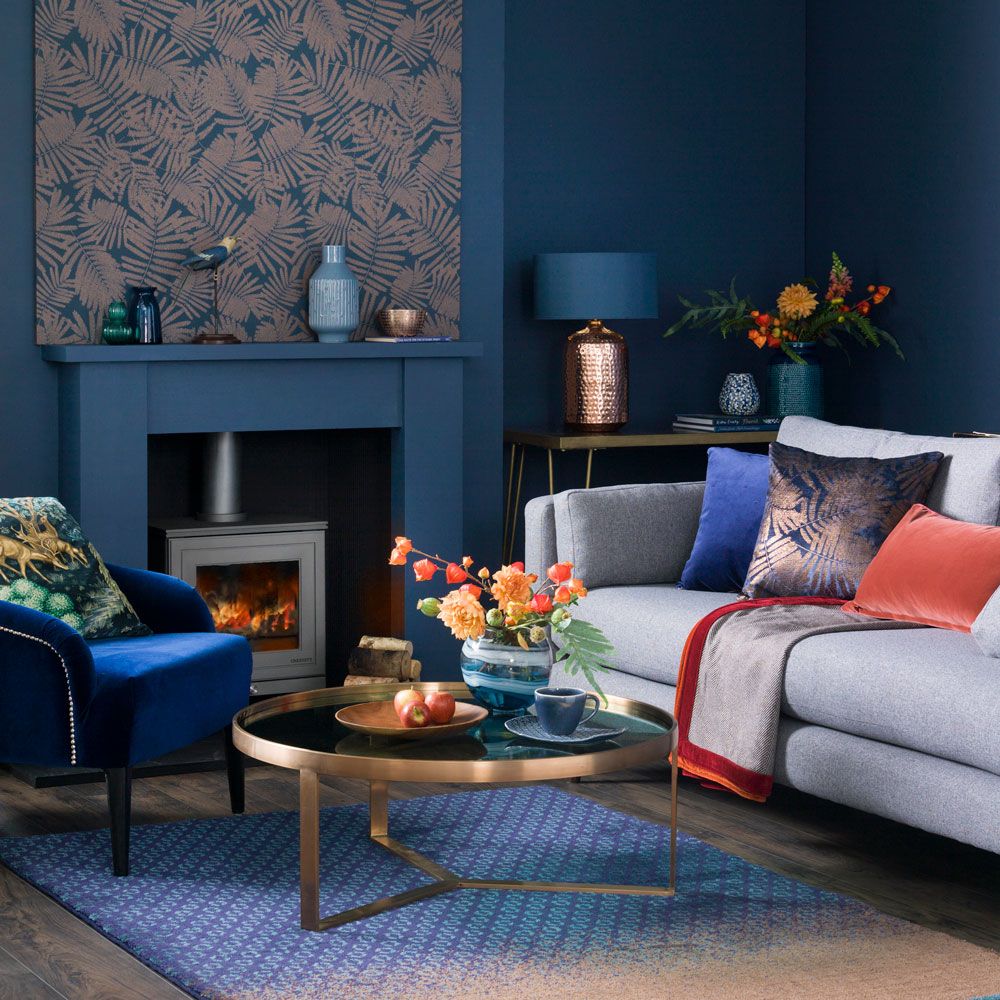 <p>                     Enrich a deep blue living room with the addition of luxurious textures and materials in a range of equally rich accent colours. In this striking blue living room deep blue walls are enhanced by a large papered art on the wall and glam metallic furniture finishes and accessories.                   </p>                                      <p>                     Luxe velvets in deep shades of burnt orange punctuate the cocooning blue beautifully, creating a moody, decadent vibe.                   </p>