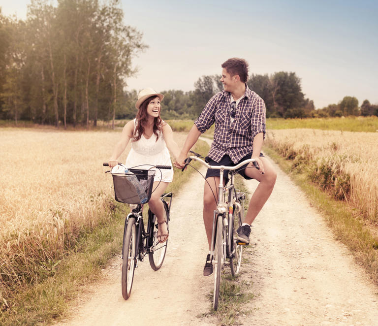 Couple riding bikes along a country road.