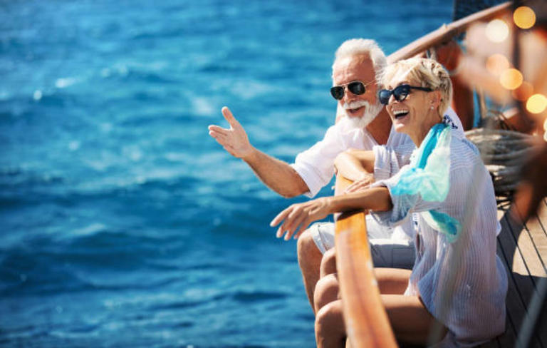 Closeup side view of mid 60's couple enjoying a sailing cruise during summer vacation at seaside.