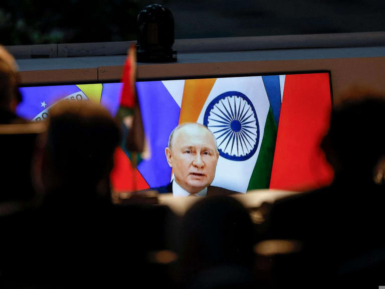 A screen shows Russian President Vladimir Putin virtually delivering remarks as delegates look on while attending a meeting during the 2023 BRICS Summit at the Sandton Convention Centre in Johannesburg on August 24, 2023.