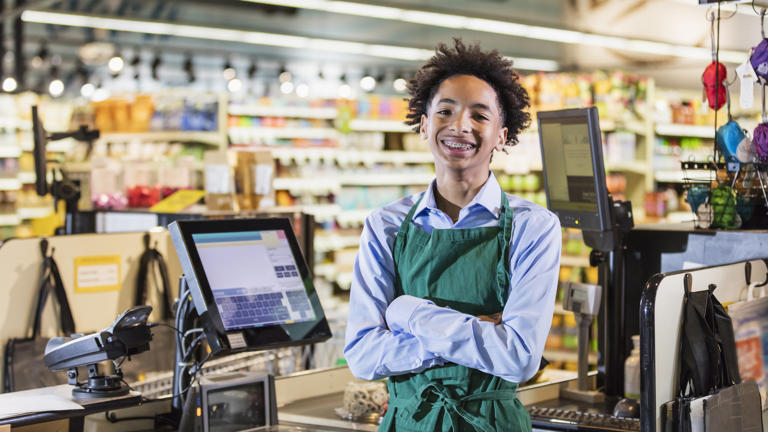 Mixed race teenage boy working as supermarket cashier