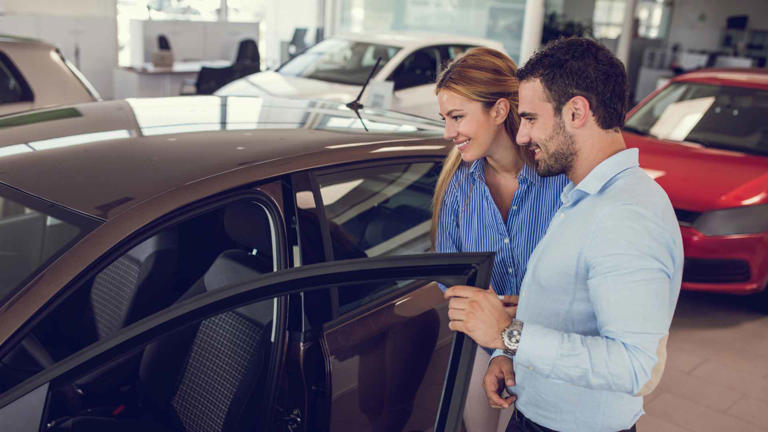 Young couple at car dealership looking at new car together.