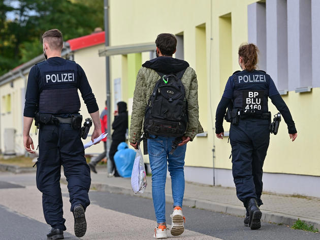 Zwei Beamte der Bundespolizei begleiten einen Flüchtling auf dem Gelände der Zentralen Erstaufnahmeeinrichtung für Asylbewerber