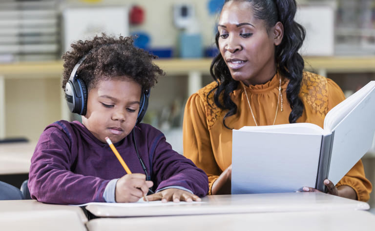 An African-American teacher with an elementary school student in the classroom. The student is an 8 year old boy. Noise canceling headphones can be helpful to a child with learning difficulty. (Photo: kali9 via Getty Images)