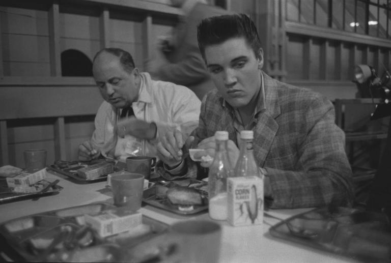Elvis Presley eating breakfast with Colonel Tom Parker the day he was conscripted into the US Army in 1958. Credit / Don Cravens / Getty.